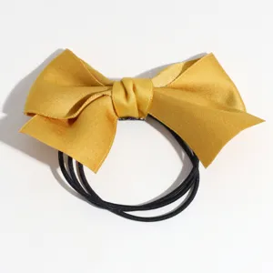 Détail chouchou nœud satin doré, élastique queue de cheval simple unie pour coiffure quotidienne.