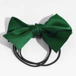 Gros plan sur le détail de l'élastique à cheveux nœud en satin vert foncé, élégant.