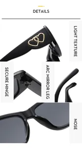 Close-up details of black cat-eye sunglasses featuring metal double heart temples and hinges.