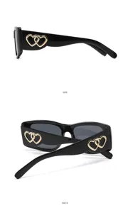 Detail view of stylish black sunglasses with golden double heart accent on the sleek temple.