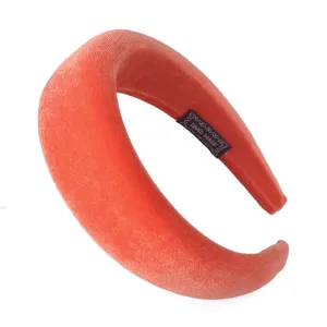 Detailed view of the coral red velvet padded headband, showing soft texture and fine handmade label.