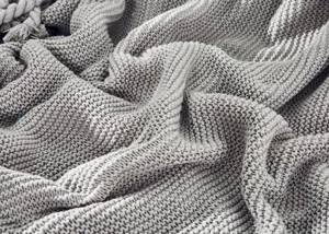 Graue gestrickte Decke Detail Nahaufnahme, gemuetliche dicke Wolle Textur Sofa Bett.