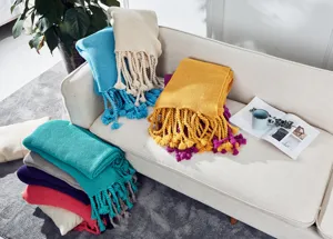 Gemütliche Strickdecke mit Fransen in Wohnzimmerszene, perfekt für warme Sofadekoration.