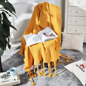 Nahaufnahme der nordischen einfarbigen Strickdecke mit Fransen in sanftem Gelbton.