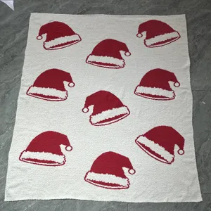 Vue detaillee de la couverture de noel en peluche blanche avec des motifs de bonnet du pere noel.