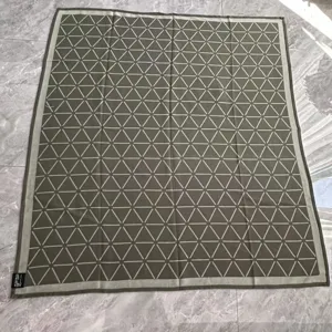 Detail view of woven jacquard blanket featuring geometric triangle grid pattern, green textile.