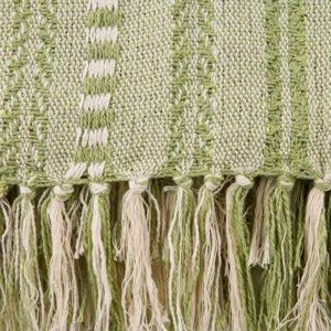 Detail de couverture jacquard tisse avec motif ethnique vert et franges elegant.