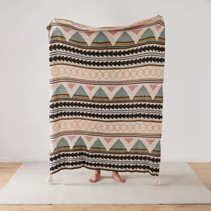 Knitted jacquard throw blanket with geometric triangle pattern and tassel balls for sofa bed decor.