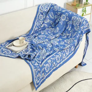 Detail view of a blue and grey jacquard woven throw blanket draped gracefully over a beige sofa.