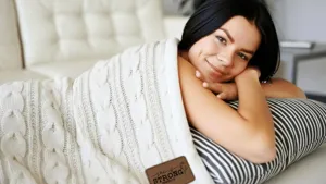 Cozy white cable knit blanket detail shot, thick soft woven throw for winter sofa bed warmth.