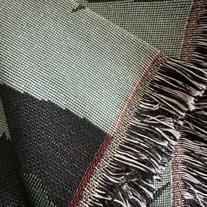 Nahaufnahme einer bohemian gewebten Picknickdecke mit feiner Textur und Fransenrand.