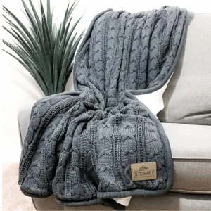 Dark grey knitted cable throw blanket with thick sherpa backing for cozy winter home decor.