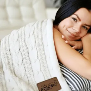 Cozy knitted cable blanket for winter, thick cream throw blanket with inspirational leather patch.