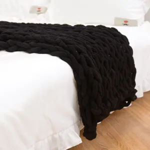 Detailaufnahme der schwarzen grob gestrickten Decke, weiche handgemachte Textur fürs Sofa.