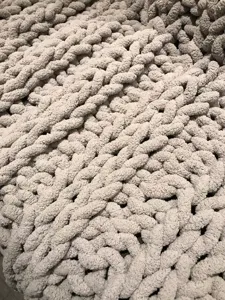 Nahaufnahme der grob gestrickten Chenille-Decke, kuscheltiefe weiche Textur als Sofaüberwurf.