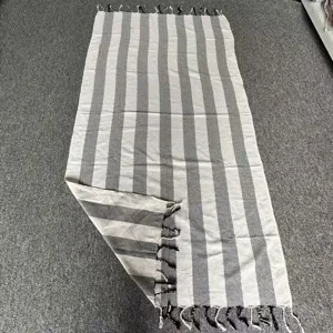 Dettaglio asciugamano mare cotone rigato grigio bianco con consistenza morbida frange.