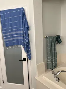 Detailed view of Turkish striped beach towel hanging in bathroom showing fringe and texture.