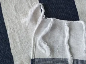 Primo piano dettagliato del bordo tessile sfrangiato morbido con nappe finemente annodate.