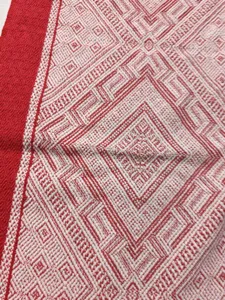 Gros plan détaillé du tissu de chemin de table tissé rouge et blanc à motif géométrique.