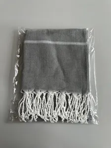 Dettaglio dell'asciugamano turco grigio piegato con classiche strisce bianche e frange.