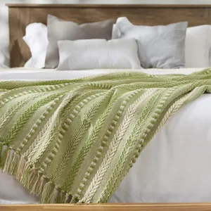 Vue détaillée de la couverture tissée à franges jacquard, jeté de canapé vert et beige style ethnique.