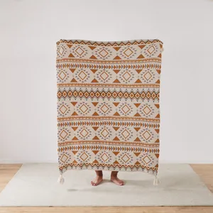 Close-up of knitted jacquard throw blanket with geometric diamond pattern and cute tassels.