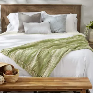 Beau plaid tissé vert avec des détails de franges élégants sur un lit de chambre.