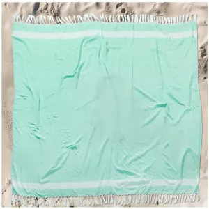 Detail shot of mint green Turkish beach towel featuring white stripes and delicate fringe tassels.