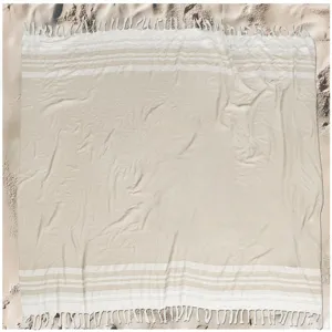 Close-up detail of soft Turkish beach towel with striped pattern and tassels on sand.
