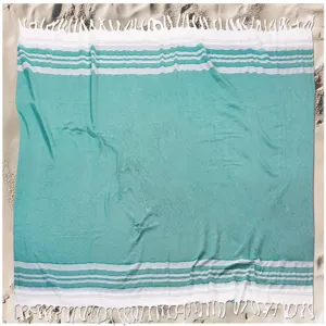 Close-up detail of the teal Turkish beach towel showcasing striped weave and fringe.