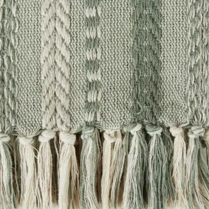 Gros plan de la couverture en jacquard tissé montrant un motif texturé et des franges.