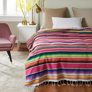 Colorful striped Mexican blanket detail in cozy bedroom scene with vibrant woven texture.
