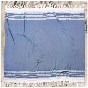 Turkish cotton beach towel with blue and white stripes and fringe detail for summer vacation.