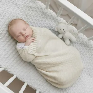 Close-up detail of soft knitted baby swaddle blanket in beige, cozy for autumn and winter.