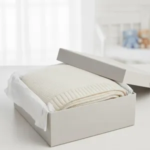 Cozy knitted baby blanket detail in elegant gift box, soft texture for warm home comfort.
