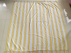 Yellow and white striped Turkish cotton beach towel with tassels, soft and absorbent.