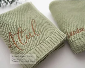 Custom embroidered knit baby blanket closeup showing soft sage green texture and personalized name.