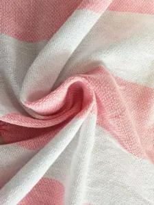 Detailed view of soft pink and white striped cotton Turkish beach towel fabric texture.