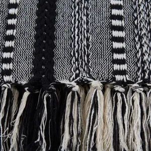 Gros plan sur la texture de la couverture jeté en jacquard tissé noir et blanc avec franges.