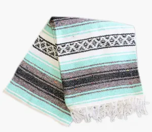 Close-up detail of the woven Mexican blanket showcasing vibrant mint green stripes and fringe.
