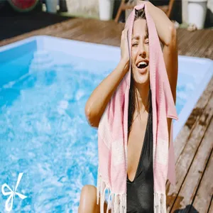 Pink Turkish cotton beach towel with striped pattern and chic fringe detail for summer pool.