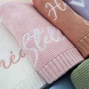 Closeup detail of soft knitted cotton baby blanket with custom name embroidery cozy texture.