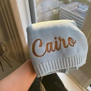 Close-up of personalized baby knitted blanket with custom Cairo embroidery in soft cotton fabric.