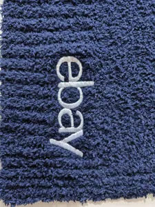 Close-up detail of dark blue fleece blanket texture with embroidered logo lettering.