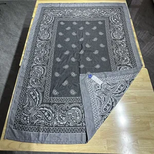 Vista dettagliata della coperta jacquard tessuta con motivo paisley classico in grigio.