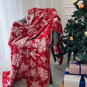 Detailed view of a red and white knitted Christmas throw blanket with Nordic snowflake pattern.