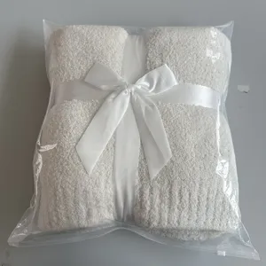 Cozy fuzzy knit throw blanket in solid white with elegant satin ribbon bow packaging for winter warmth.