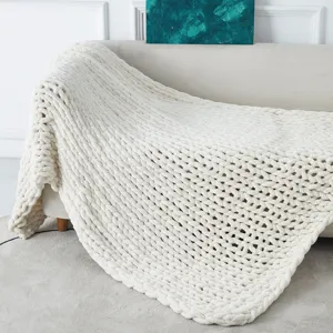 Detailed scene view of soft white chenille chunky knit blanket draped elegantly on cozy sofa.