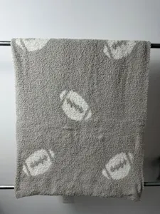 Dettaglio coperta in maglia soffice grigia con texture in peluche morbida e motivo jacquard.
