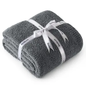 Close-up of folded dark grey fleece blanket with white ribbon detail, soft and cozy fabric.